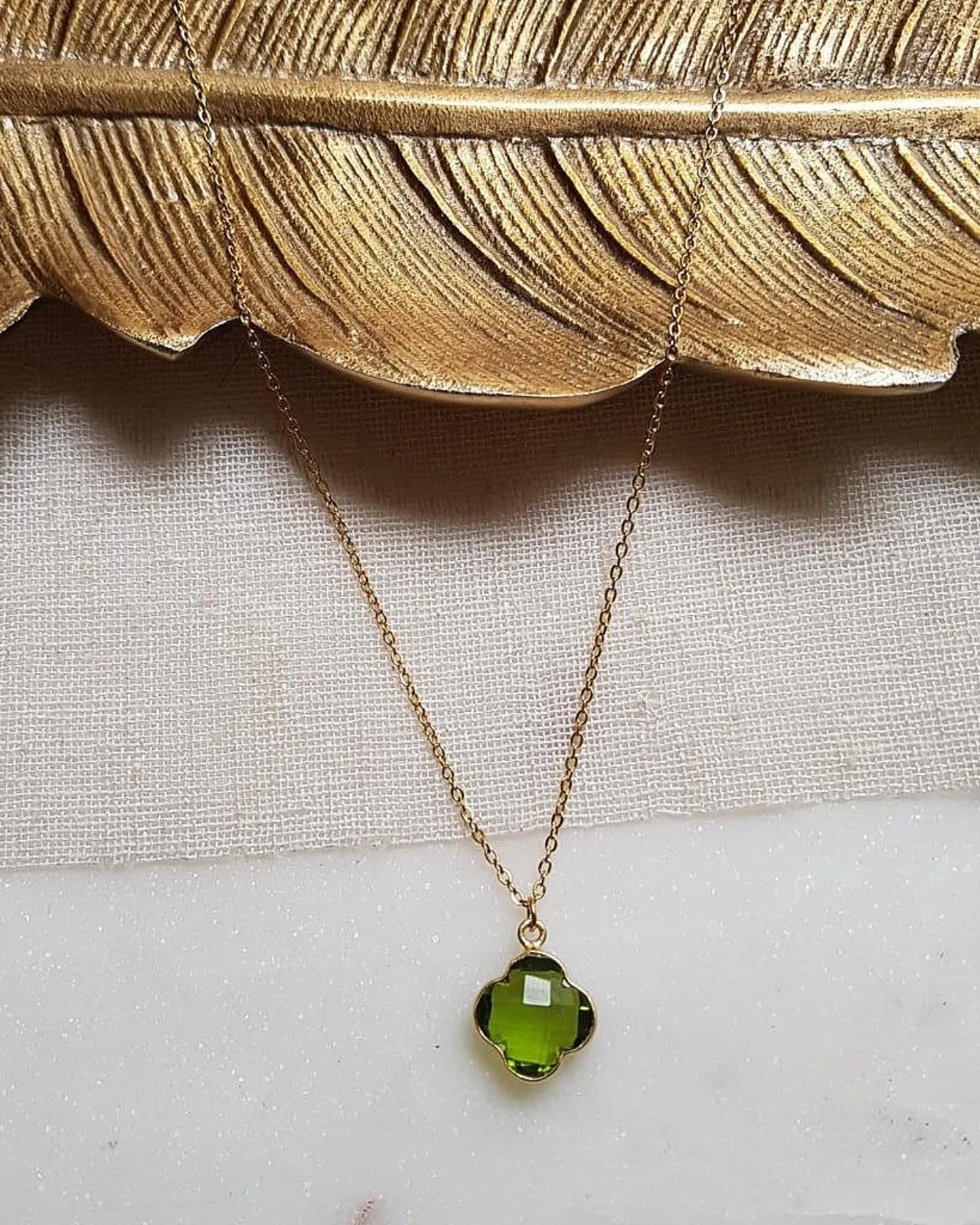 Primo piano del ciondolo a forma di quadrifoglio con pietra peridoto verde naturale sfaccettata, talismano portafortuna