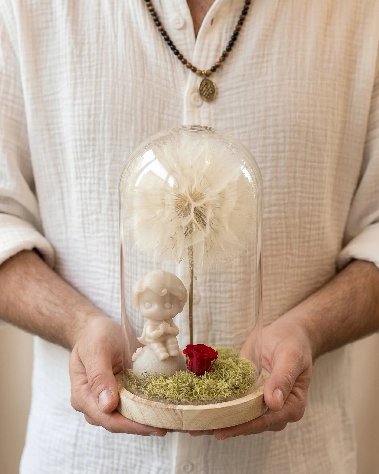 Mani che tengono la campana di vetro L'Essentiel — composizione botanica ispirata a Le Petit Prince, Io Sono La Luce Roma.