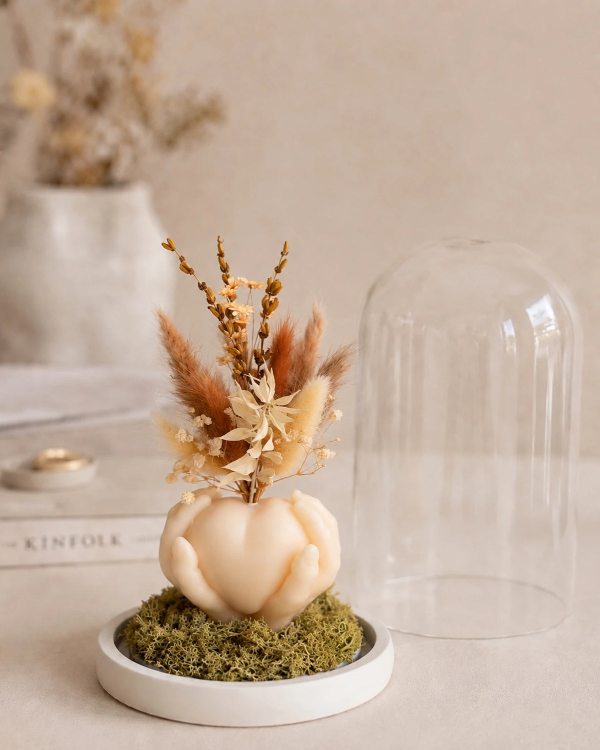 Carinho: composizione di fiori secchi in vaso di cera a forma di cuore sorretto da mani con campana di vetro e base di legno - Io Sono La Luce Roma | Colore grano