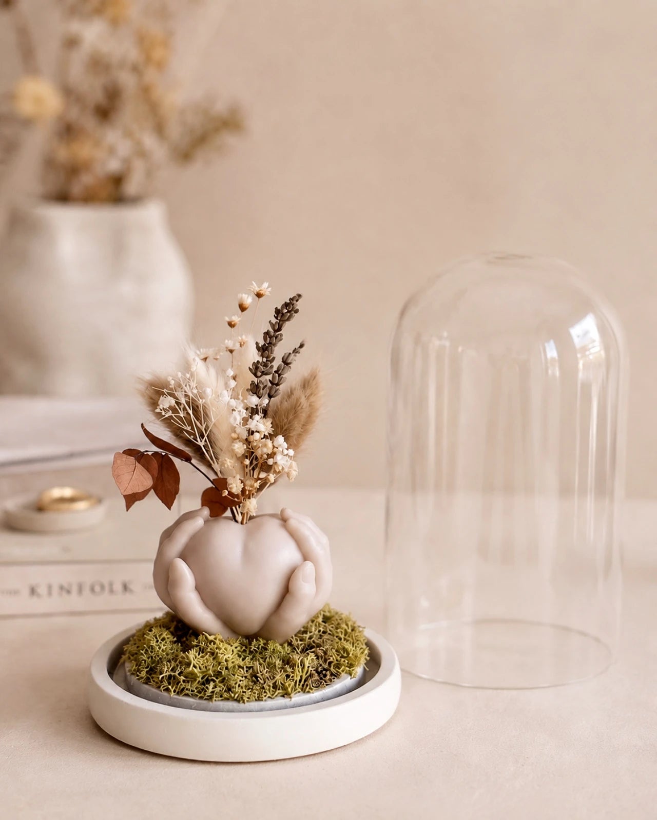 Carinho: composizione di fiori secchi in vaso di cera a forma di cuore sorretto da mani con campana di vetro e base di legno - Io Sono La Luce Roma | Colore sabbia