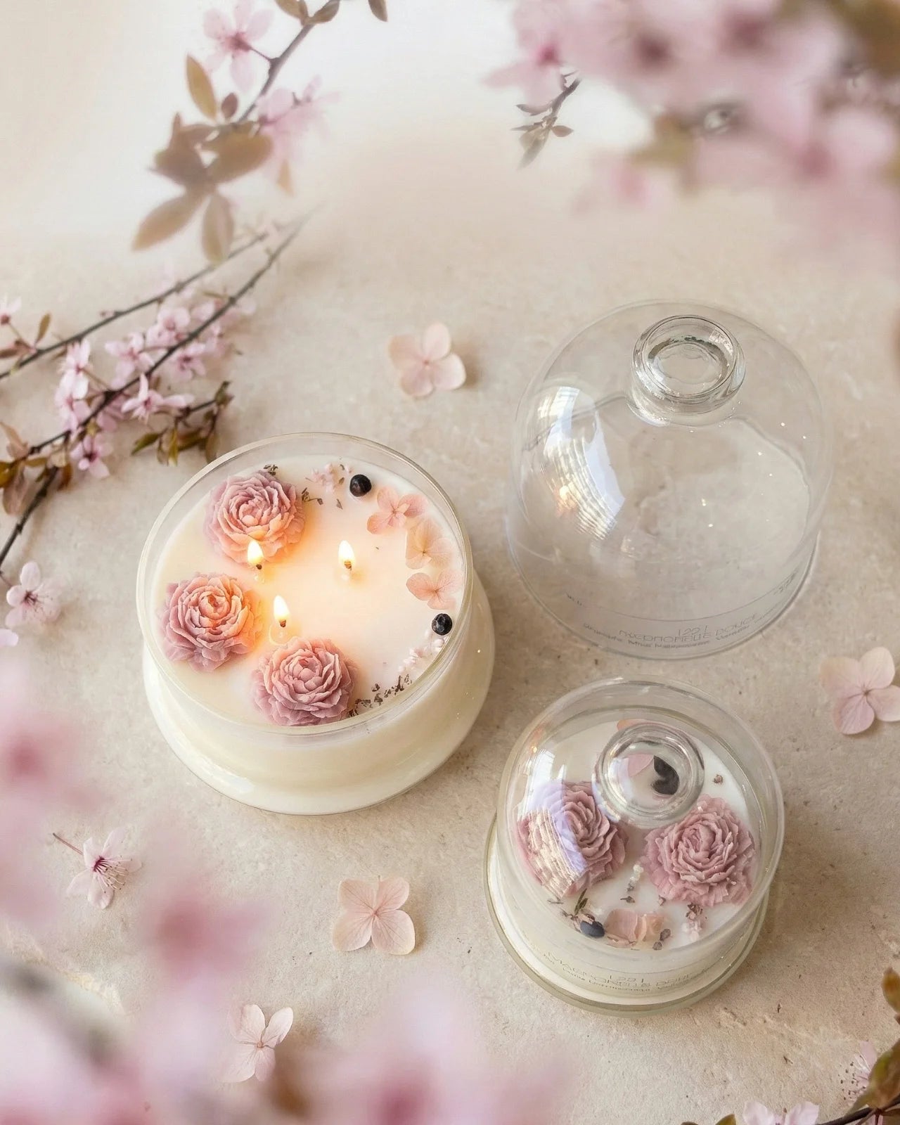 Candela botanica Hanami con campana di vetro, fiamme danzanti e composizione di petali e fiori essiccati con fiorellini di cera ispirata alla fioritura dei ciliegi giapponesi 