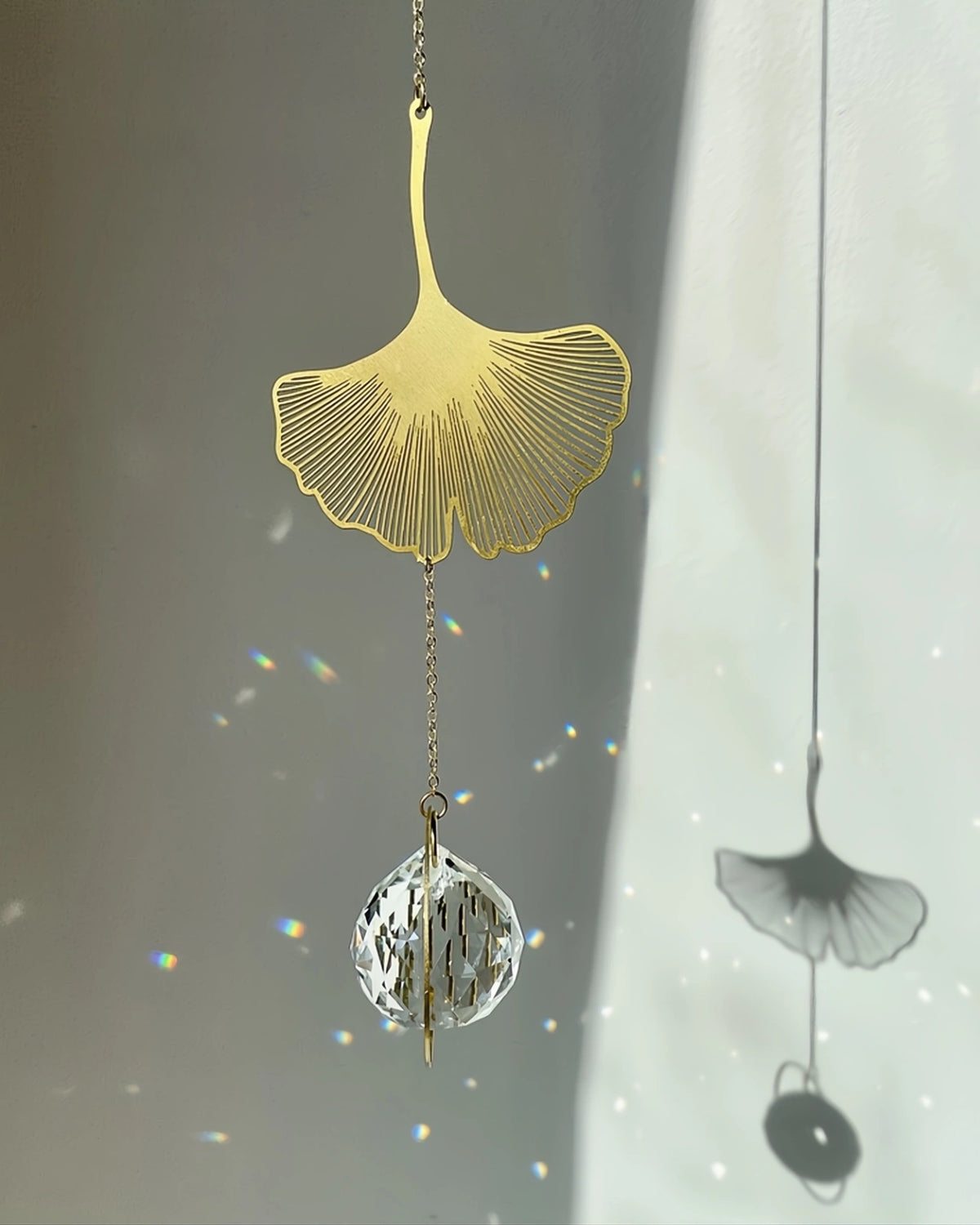 Suncatcher Heliophilia - Acchiappasole feng shui artigianale che crea arcobaleni di luce con cristallo sfaccettato e simbolo in ottone foglia di ginko