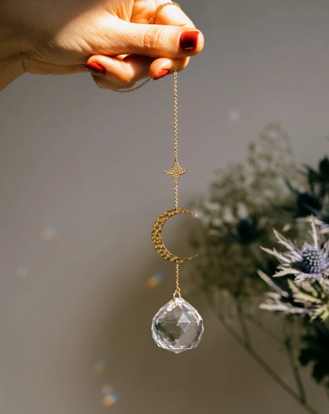 Suncatcher Heliophilia - Acchiappasole feng shui artigianale che crea arcobaleni di luce con cristallo sfaccettato e simbolo in ottone in mano