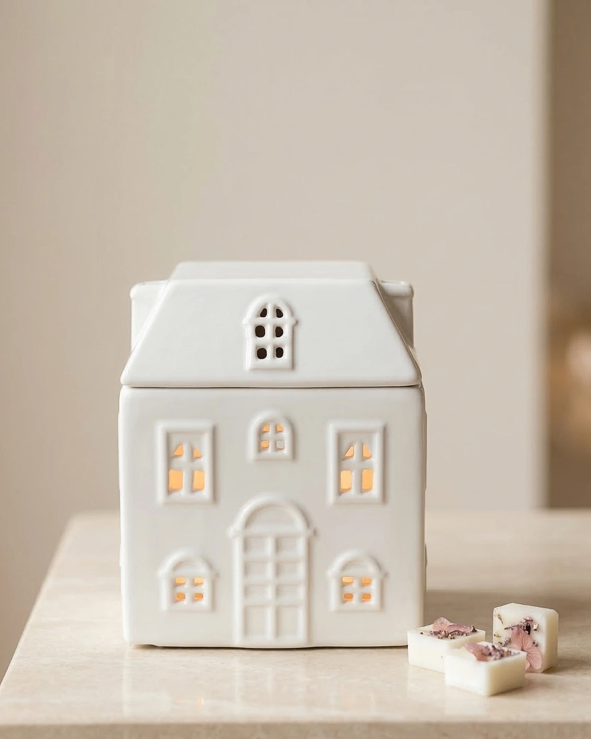 Bruciatore di cera in ceramica bianca a forma di casetta Akari No Ie, vista frontale con finestrelle ritagliate
