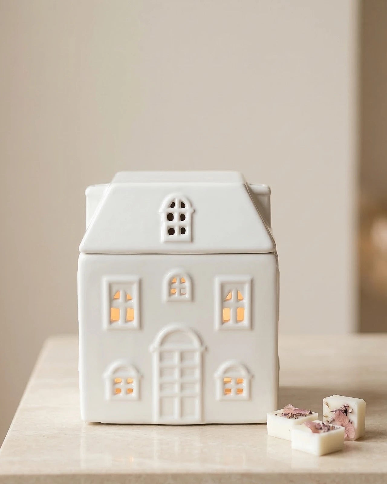 Bruciatore di cera in ceramica bianca a forma di casetta Akari No Ie, vista frontale con finestrelle ritagliate
