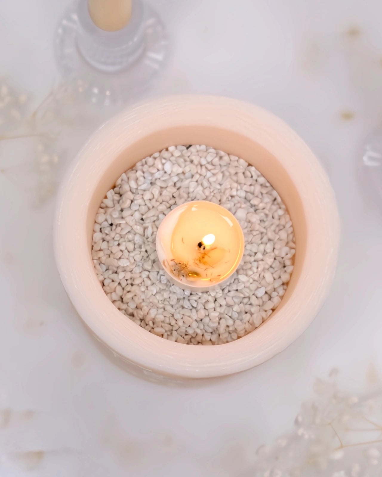vista zenitale del vaso con sassolini bianchi e tealight accesa al centro