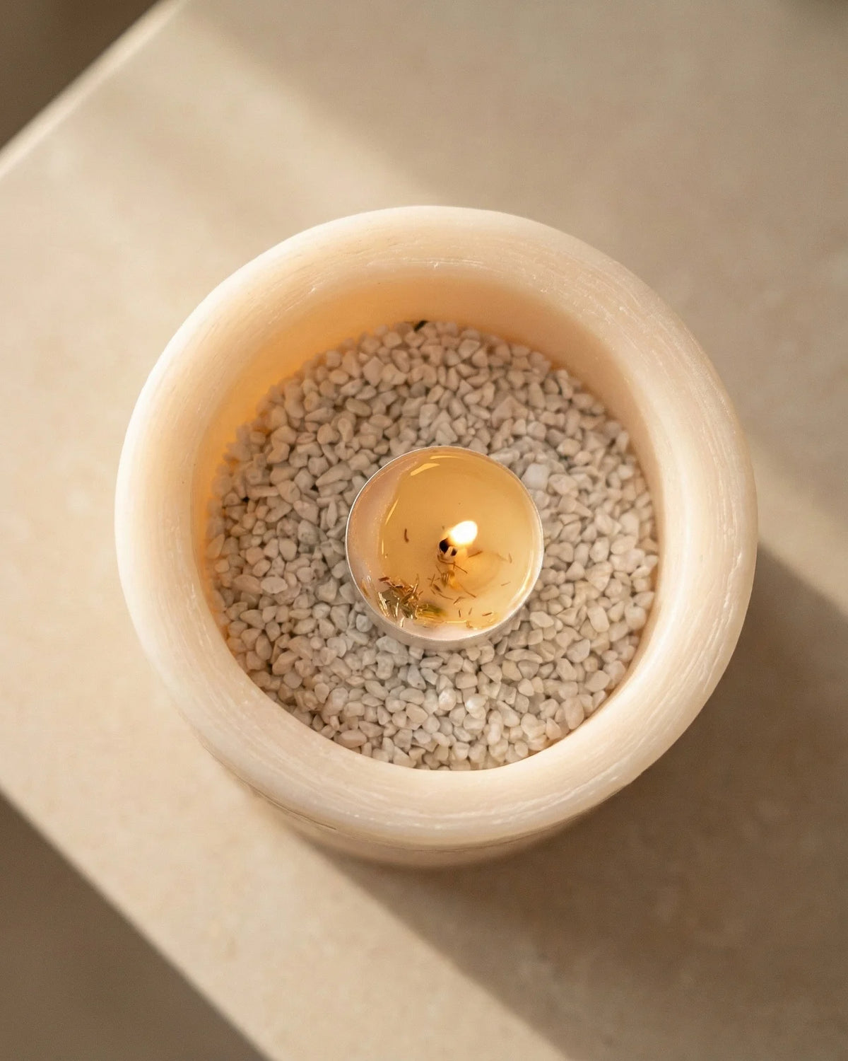 vista zenitale del vaso con sassolini bianchi e tealight accesa al centro