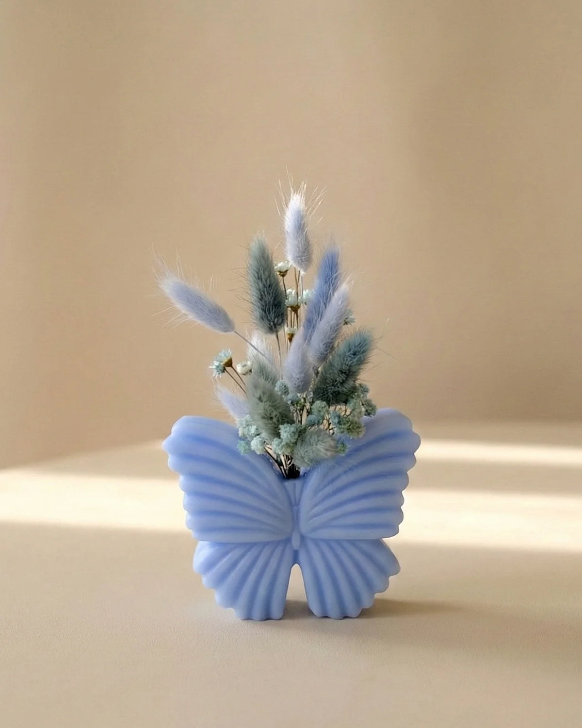 Vaso di cera a forma di farfalla con bouquet di fiori secchi e stabilizzati, creazione artigianale simbolo di rinascita color carta da zucchero