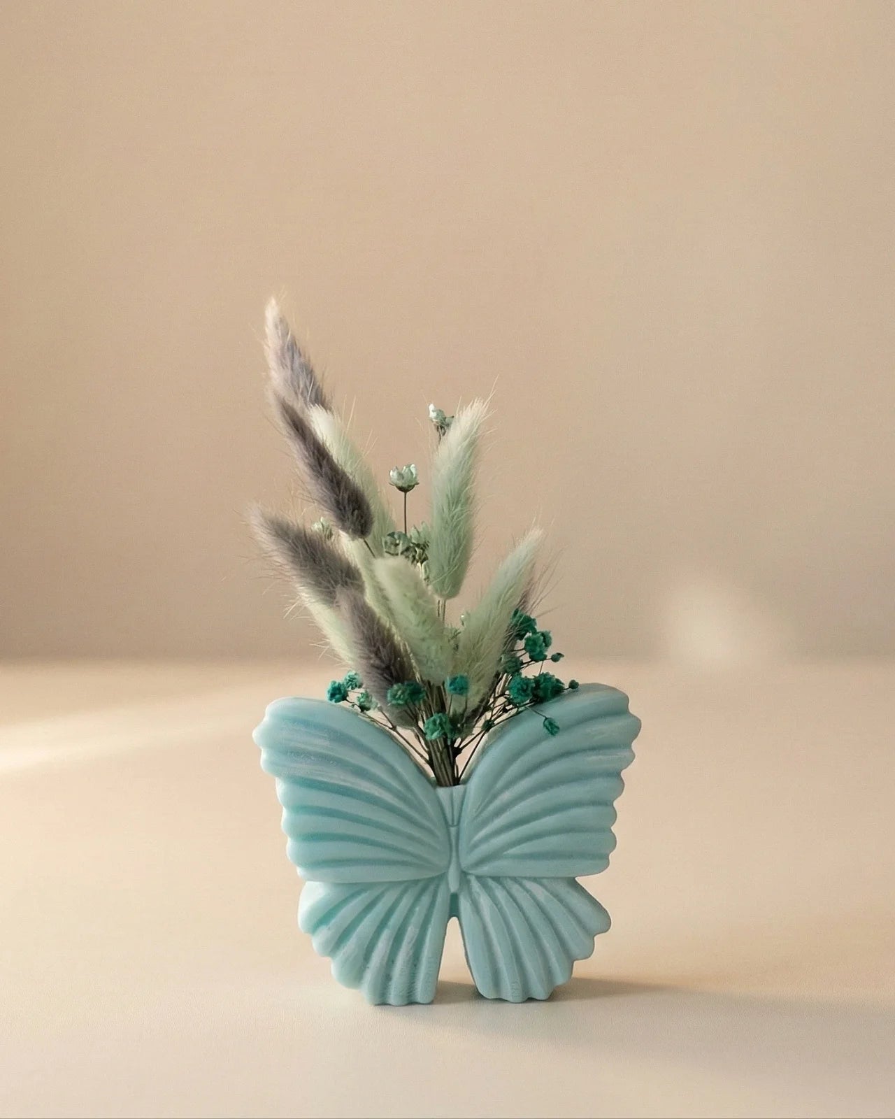 Vaso di cera a forma di farfalla con bouquet di fiori secchi e stabilizzati, creazione artigianale simbolo di rinascita color turchese stardust