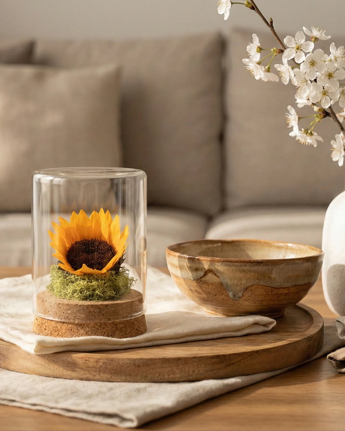 Girasole sotto vetro su coffee table in legno con ciotola ceramica e tessile naturale, decor japandi zen